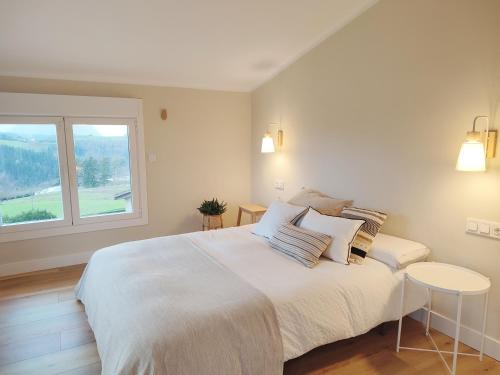 Un dormitorio blanco con una cama grande y una ventana en Areitio etxea - casa con jardin, en Mallavia