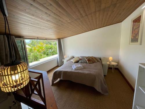 a bedroom with a bed and a large window at Villa la Playa pieds dans l'eau lagon + piscine in Saint-Gilles les Bains