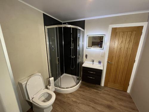 a bathroom with a shower and a toilet and a sink at Rowan Boutique Lodge for couples with a dog in York