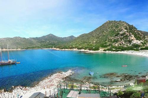a view of a beach with a boat in the water at SUPER APPARTAMENTO TERRAZZA PANORAMICA 3 CAMERE in Villasimius