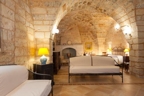 um quarto com 3 camas num quarto com paredes de pedra em Agriturismo Masseria Chicco Rizzo em Sternatia