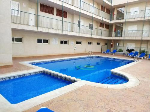 a large swimming pool in a building with blue chairs at 2 bed penthouse, Bolnuevo in Bolnuevo