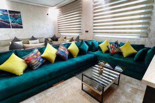 a living room with a green couch with colorful pillows at Appartement Emeraude - Calme, Moderne & Sécurisé in Fès