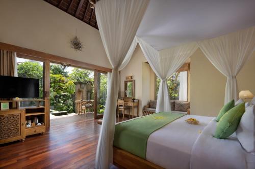 a bedroom with a bed and a television in a room at The Alena a Pramana Experience in Ubud