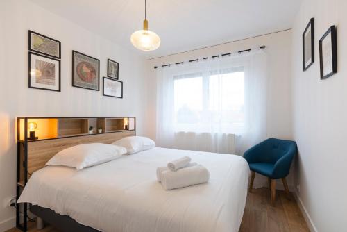 um quarto com uma cama branca e uma cadeira azul em Le Placieux avec parking privé em Nancy
