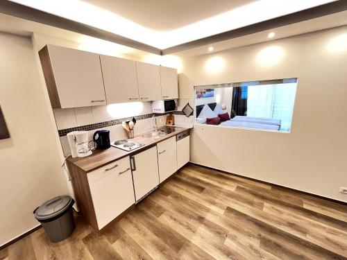 a kitchen with white cabinets and a wooden floor at Pension am Schloss in Schwerin
