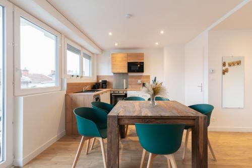 uma cozinha e sala de jantar com uma mesa de madeira e cadeiras verdes em Le Placieux avec parking privé em Nancy