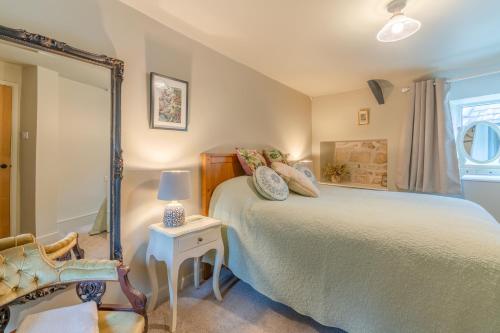 - une chambre avec un grand lit et une chaise dans l'établissement Cotswold Way Cottage, à Stroud