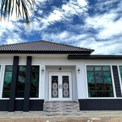 uma casa branca com uma porta branca e janelas em Qs Family Homestay Pasir Mas em Pasir Mas
