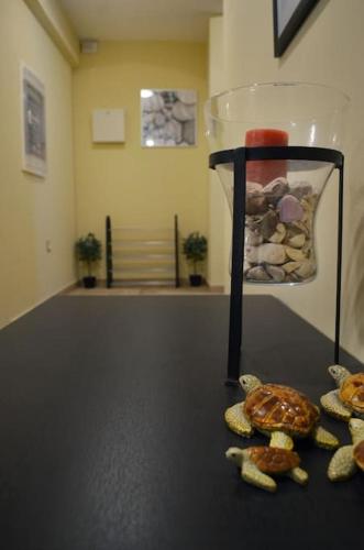 a table with a glass vase with rocks in it at ΤΟ ΠΕΤΡΙΝΟ - Καλοκαιρινό Σπίτι κοντά στα Σύβοτα - ΦΑΣΚΟΜΗΛΙΑ in Faskomiliá