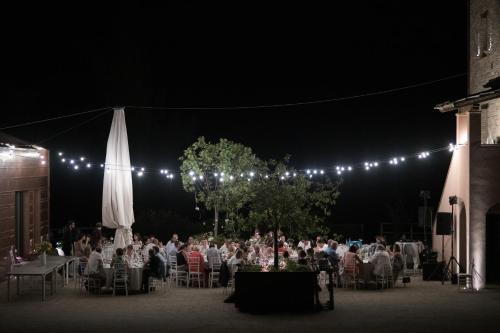 eine Gruppe von Menschen, die nachts an Tischen sitzen in der Unterkunft Agriturismo Colle Casini Cortesi in Caldarola