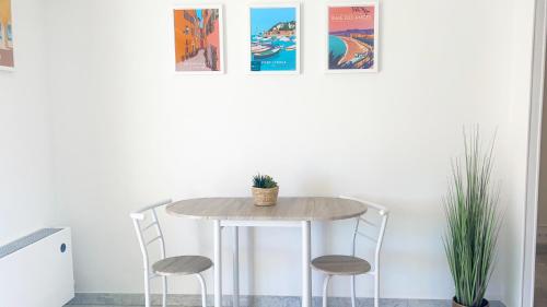 une table dans une pièce avec deux chaises et des affiches dans l'établissement La Couronne du Cros, à Cagnes-sur-Mer
