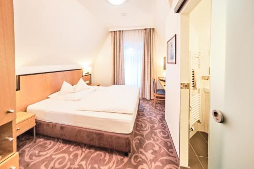 ボンにあるホテル ハウス ベルリンのベッドとデスクが備わるホテルルームです。