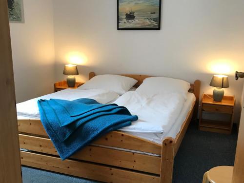 a bedroom with a wooden bed with a blue towel on it at Pension Martens - Ella in Wieck
