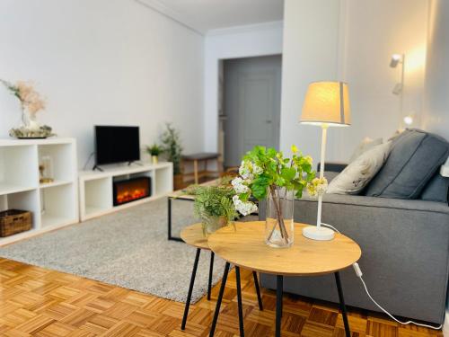 uma sala de estar com um sofá e uma mesa com flores em Asturias City and Sea em Oviedo