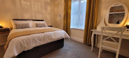a bedroom with a bed and a desk and a window at Data House Holiday Apartment in Atherstone