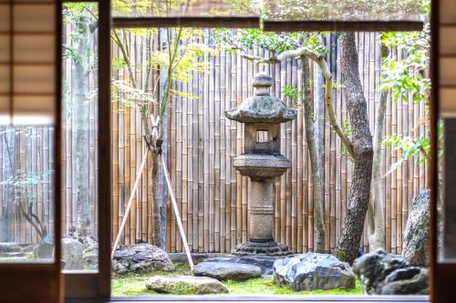 a stone birdbath in a garden in front of a fence at Tansada Heritage Machiya in Kyoto