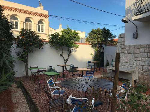 eine Terrasse mit Tischen, Stühlen und einem Sonnenschirm in der Unterkunft LA CASA SANILLS in Saint-Hippolyte