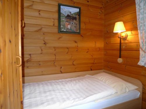 a bed in a wooden room with a picture on the wall at Landhaus Meyer in Riefensbeek