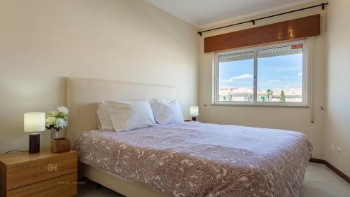 Un dormitorio con una cama grande y una ventana en T1 Grevilias em Vilamoura - Greice Homes en Quarteira