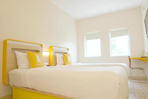 a white bedroom with a large bed with yellow pillows at Bloomrooms Calangute in Calangute