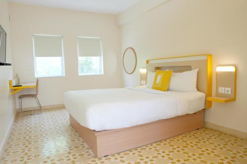 a bedroom with a large white bed and a desk at Bloomrooms Calangute in Calangute