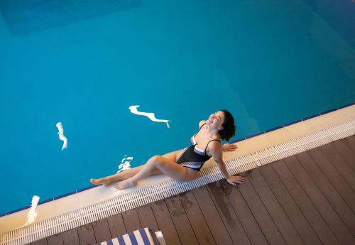 a woman in a swimsuit laying next to a swimming pool at Ramada by Wyndham Tbilisi Old City in Tbilisi City