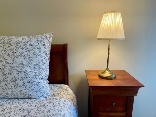 een lamp op een nachtkastje naast een bed bij Le Mulberry in Bayeux