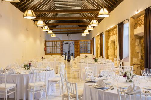 einen Bankettsaal mit weißen Tischen und Stühlen in der Unterkunft Hotel Tugasa Convento San Francisco in Vejer de la Frontera