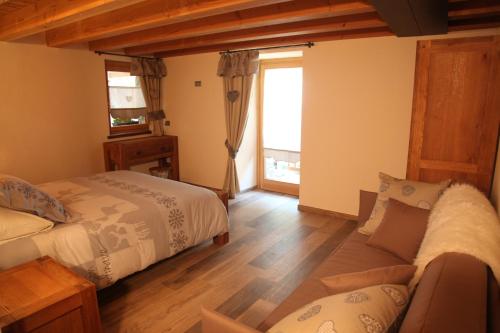 a bedroom with two beds and a couch and a window at Mi Casa Tu Casa in Brusson