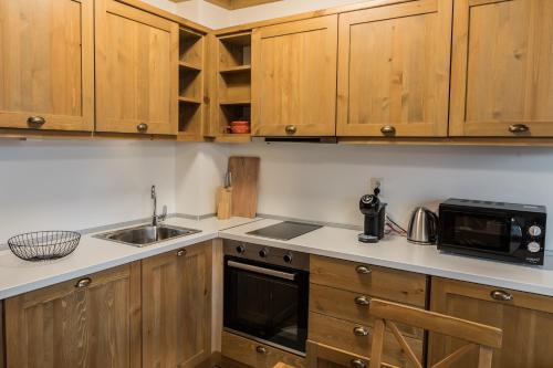 La cuisine est équipée de placards en bois, d'un évier et d'un four micro-ondes. dans l'établissement Pirin Golf and Spa Cozy Studio, à Bansko
