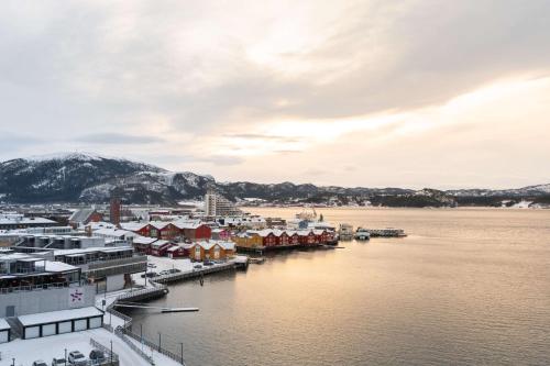 a town on the water with snow covered buildings at Scandic Rock City in Namsos