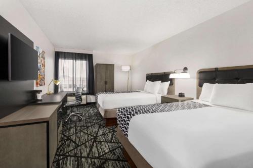 a hotel room with two beds and a desk at La Quinta by Wyndham Cleveland Airport West in North Olmsted