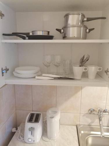 a kitchen with a shelf with dishes and pots and pans at Dom Gościnny Posejdon in Pobierowo
