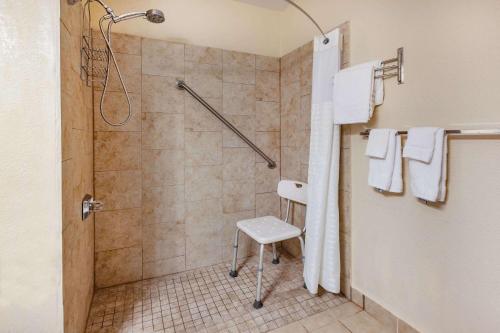 y baño con ducha y silla blanca. en Baymont by Wyndham Perrysburg-Toledo, en Perrysburg