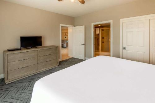 a bedroom with a bed and a flat screen tv at Escapes! To The Shores Orange Beach, A Ramada by Wyndham in Orange Beach