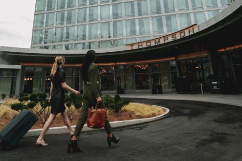 two women walking in front of a building with luggage at Thompson Atlanta Buckhead, part of Hyatt in Atlanta