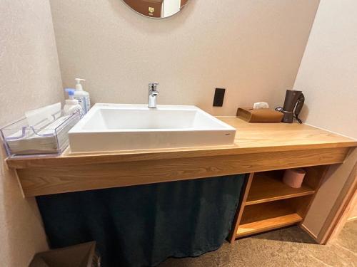 a white sink on a wooden counter in a bathroom at Sangai Ryokan in Gotsu