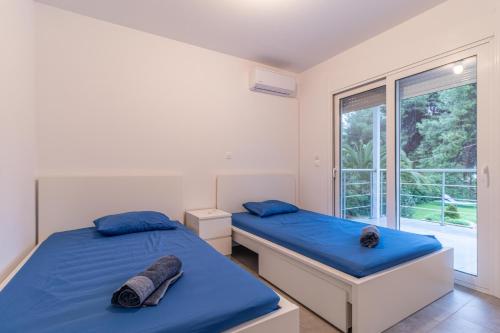 two beds in a room with a window at Marvelous, Secluded Villa w/ 3 BR , Pool & Garden, Kavos in Isthmia