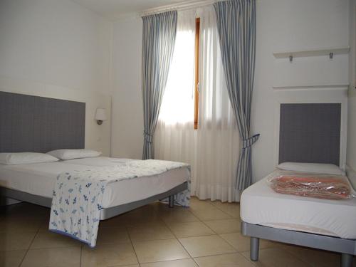 1 dormitorio con 2 camas y una ventana con cortinas en Bright apartment with swimming pool - Beahost en Bibione