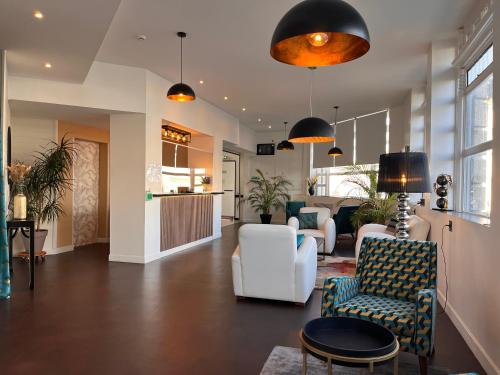 - un hall avec des chaises blanches et une réception dans l'établissement Hôtel Le Keroman, à Lorient