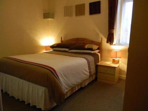 a bedroom with a large bed with two lights on at OYO Dora Hotel in Blackpool