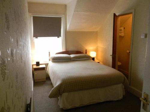 a bedroom with a large bed with a window at Dora Hotel in Blackpool