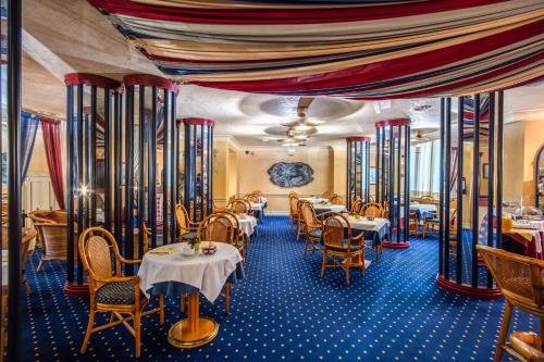 ミラノにあるホテル アウリーガのテーブルと椅子が備わるレストラン