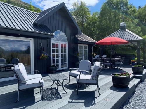a deck with chairs and tables and a red umbrella at Little Fox Lodge Luxury Hideaway with Hot Tub Glencoe Near Fortwilliam in Glencoe