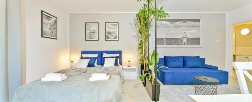 a bedroom with two beds and a blue couch at Apartamenty Rodzinne in Kołobrzeg