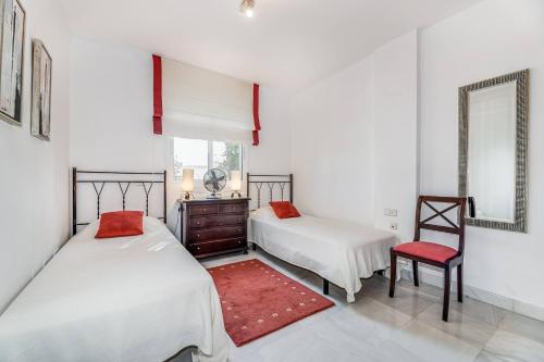 a bedroom with two beds and a chair and a mirror at Great Location, Spacious And Beautiful Apartment in Marbella