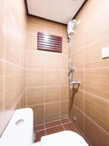 a bathroom with a toilet and a shower at Corazon Tourist Inn in Puerto Princesa City