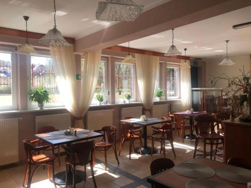a restaurant with tables and chairs and windows at Willa Anna - Pokoje Gościnne in Goczałkowice-Zdrój