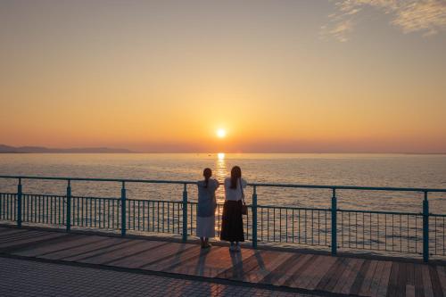 a man and woman standing on a pier looking at the sunset at OMO Kansai Airport by Hoshino Resorts in Izumi-Sano